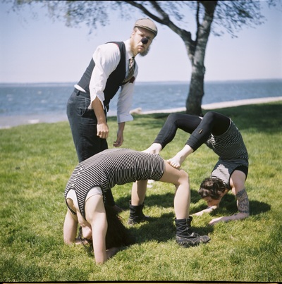 Two women in overlapping backbends, while another person looks on quizzically. 